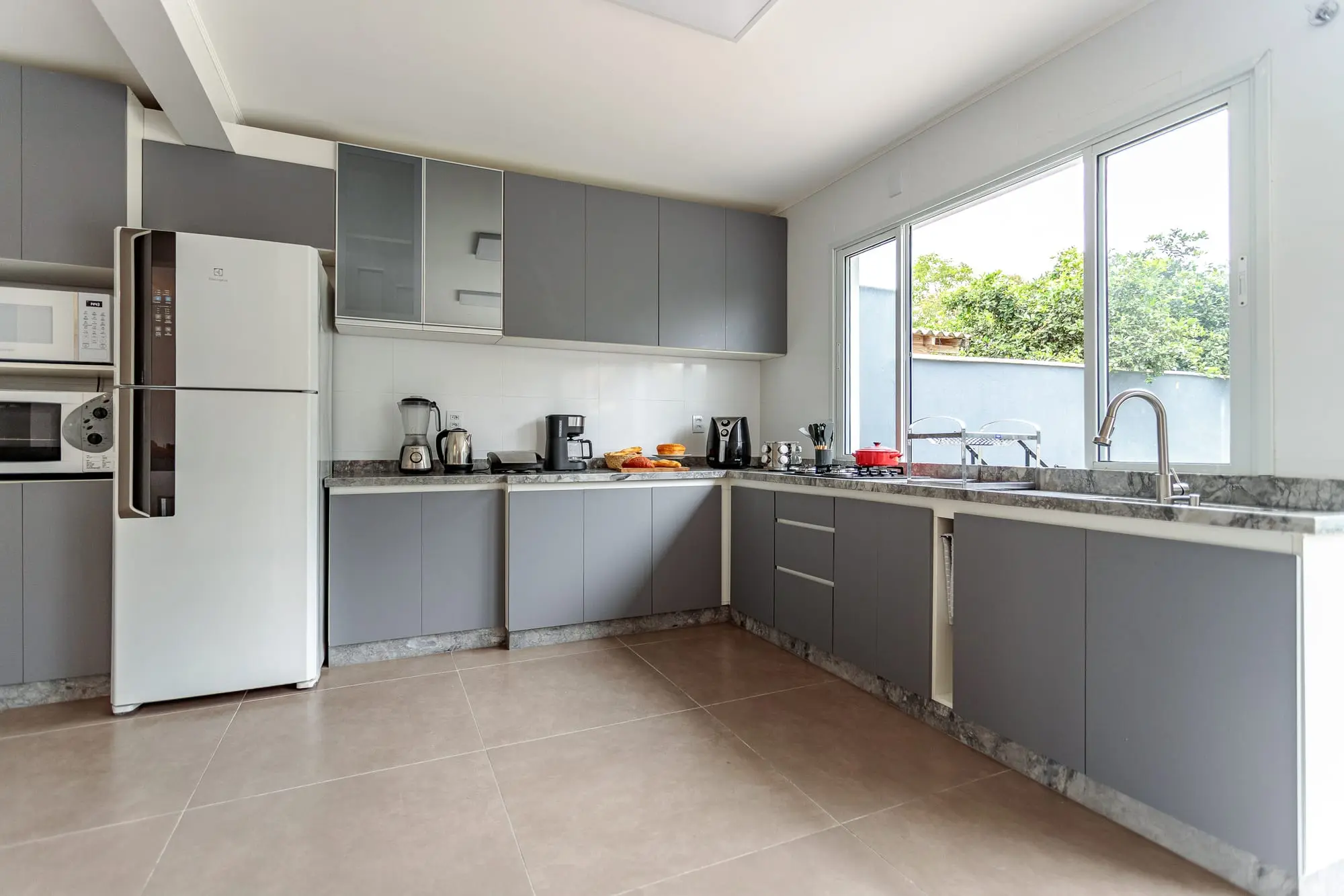 Cozinha equipada com cooktop, forno e geladeira